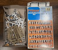 Box with unassembled and assembled HO scale Preiser passenger miniatures and parts mixed together.