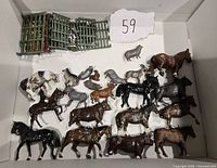 Top view of multiple metal farm animal figurines including horses, sheep, cows, and birds along with green painted metal fence sections.