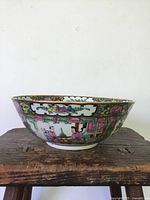 Side view of the antique Famille Rose porcelain bowl showing hand painted figures and floral decoration in pink, green, and gold.