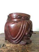 Frontal view of carved sleeping Buddha on rosewood brush pot showing detailed facial features and draped robes.