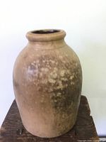 Front view of antique salt glaze primitive pottery jug showing rounded body and textured glaze.