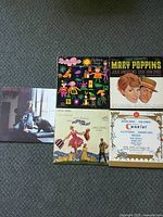 Five vinyl record albums laid out on grey textured surface showing all cover artwork.