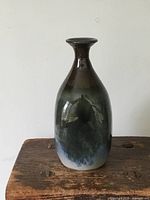 Full view of green glazed pottery vase showing tapered shape and glossy finish.