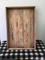Top-down view of large rustic wooden carrying tray showing interior wood planks and turquoise paint speckles.