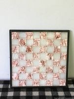 Front view of marble chess/checkers board showing alternating pink and white marble squares and dark frame, surface wear visible.