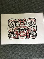 Full view of unframed North West Coast style painting showing bold black and red design on white paper with some bending visible.