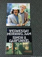 Photo showing front cover of Simon & Garfunkel Greatest Hits and Wednesday Morning, 3 A.M. vinyl records on carpet.