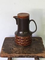 Full front view of the Beswick lidded pitcher showing the brown glaze, handle, spout, and patterned band near base.