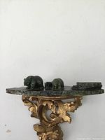 Front view of the nephrite jade bears carving on mountain base positioned on ornate golden shelf.