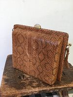 Side angle of vintage brown snake skin leather purse showing texture and clasp.
