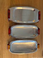 Top-down view of all three vintage stainless steel appetizer trays showing Bakelite handles in two color tones.