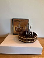 Photo showing the nut bowl, nutcracker, and nut picks with the original box behind, all placed on a wooden surface.