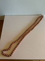 Image showing full length of copper beaded necklace laid out on a flat surface.