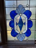 Full view of the stained glass panel showing the geometric blue and white design with beveled glass jewels and clear textured background.