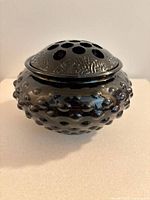 View of hobnail glass flower frog insert placed on table showing hobnail pattern and holes.