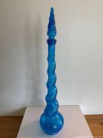 Mid-century Empoli blue glass genie bottle standing upright on a surface, showing clear visibility of the bottle’s shape and color.