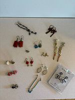 Overview photo of all 14 pairs of earrings including various styles and colors, displayed on a flat light-colored surface.
