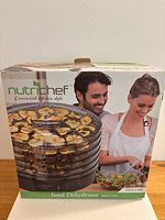 Box for NutriChef food dehydrator showing 5 trays and a couple preparing food.
