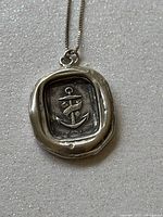 Close-up of pendant showing anchor motif with 'Hope' banner on sterling silver wax seal style oval.