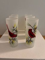 Photo showing all six frosted Tom Collins glasses with cardinal and pine branch designs, arranged in two rows.
