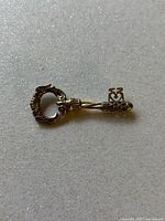 Close-up image of the ornate decorative key pendant showing the two-tone silver and gold design with intricate details.