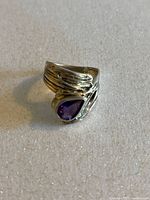 Front view showing wraparound silver band and pear-shaped amethyst gemstone.