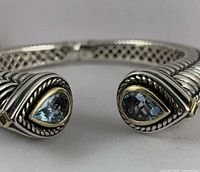 Frontal view of cuff ends showing faceted blue glass stones in 14k gold settings and rope twist silver detail