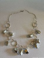 Full view of the sterling silver necklace laid flat showing large hollow nugget-shaped beads attached to a chain of mixed large round and oval links.