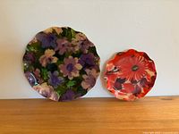 Two floral trays side by side - medium purple floral and smaller pink/red floral, showing size difference and design