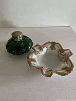 Photo of the green glass inkwell and ceramic ashtray with floral and gold details.