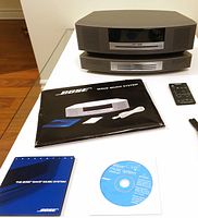 Front view of Bose Wave Music System stacked on 3-disc changer with remote, manuals and CD displayed