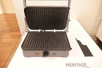 Panini grill open showing non-stick ribbed plates and indicator lights