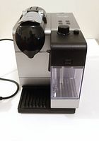 Front three-quarter view of espresso machine showing main body, milk frother attached, drip tray and power cord