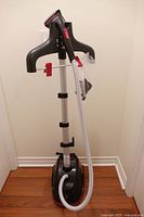 Full view of standing garment steamer with hanger, hose, and base