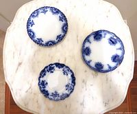 Top view of three flow blue plates showing front designs and size differences