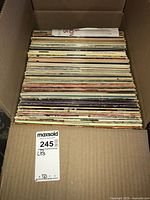 Box packed with multiple vintage vinyl LP records stacked vertically in sleeves.