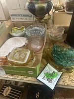 Overview of boxed and loose vintage glass ashtrays and art glass pieces on a table.