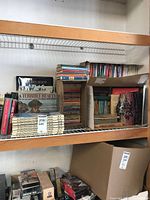 Shelf with stacked vintage paperback books and Funk & Wagnalls Wildlife Encyclopedias along with other fiction paperbacks in a cardboard box
