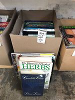 Box of assorted books including topics on world, cooking, herbs, and more.