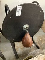 Speed bag attached to the center of a circular black board with a metal stand, showing front view of the punching target area.