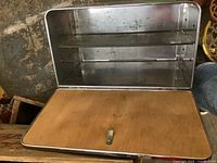 Vintage metal bread box with wooden front door visible and inside shelf seen when door is open.