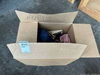 Box labeled 'HATS' containing several assorted baseball caps in different colors and patterns, overview of contents.