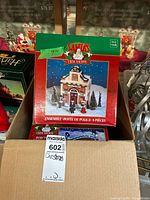 Boxed eight-piece Santa's Trim Shoppe police station building ensemble with figurines and trees.