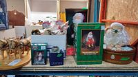 Overview of lot showing wooden reindeer, boxes of ornaments, and two large Santa figures.