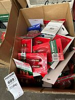 Box containing multiple packages of Christmas light replacement bulbs including flame bulbs and candle bulbs, visible brand and product labels.