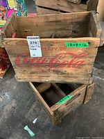 Two vintage Coca-Cola wooden crates stacked, showing faded red Coca-Cola branding and dimensions.