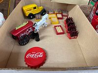 Top-down view of the lot showing cast iron vehicles, miniature crates, and bottles inside a cardboard box