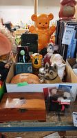 Full view of multiple coin banks including large orange bear, Santa Claus, dog and other animals, along with wooden box and packaged bear coin bank.
