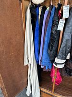 A rack with multiple Danier leather jackets in an assortment of colors and styles, including a beige trench-style jacket or dress in front.