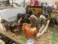 Photo showing multiple decorative horse figurines including fabric rocking horse, painted wood horse, and bronze and gold metal horses.
